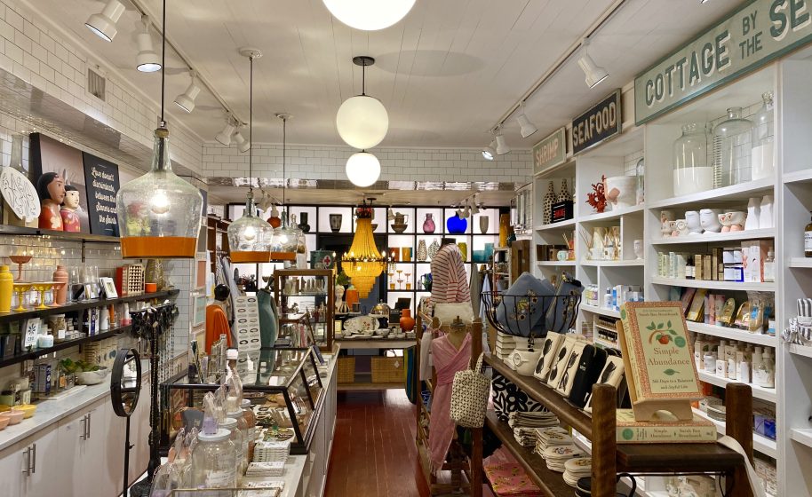Bright boutique interior with shelves of home goods, gifts, and decorative lighting.
