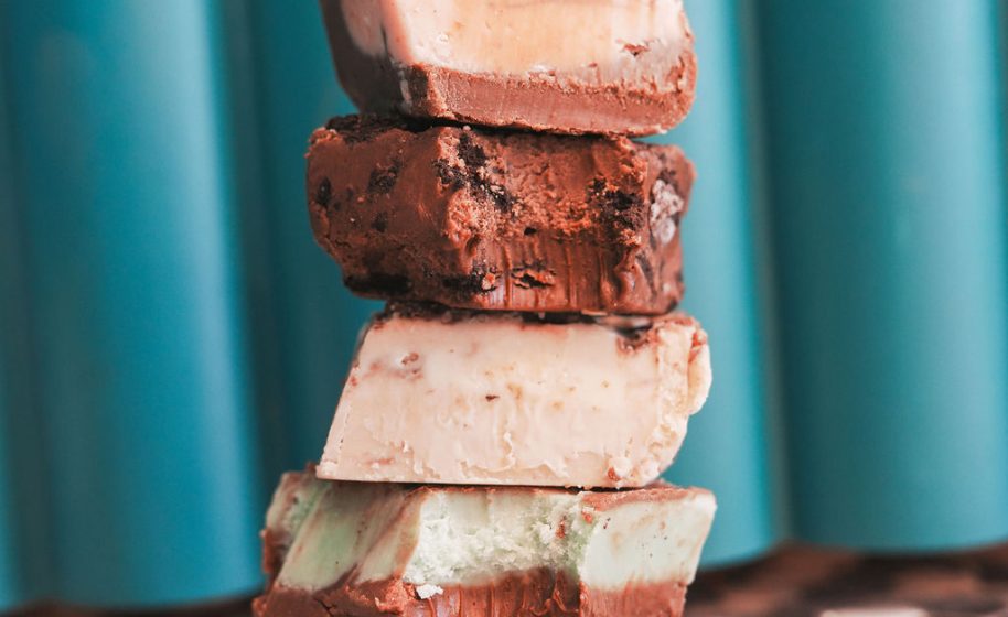 Stacked layers of assorted chocolate fudge pieces against teal background.