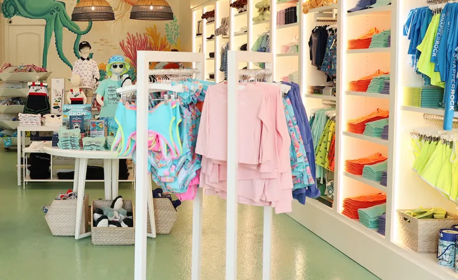 Bright, playful store interior with kids' swimwear, colorful displays, baskets, undersea mural and oversized beach balls.