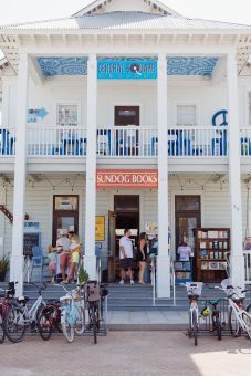 People browsing books outside Sundog Books storefront with bicycles parked in front.