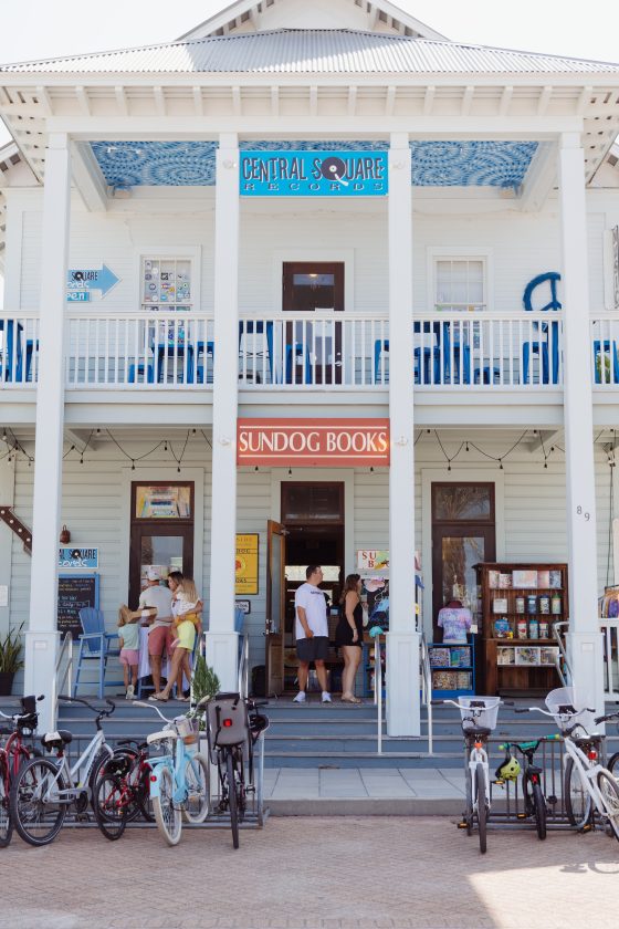 People browsing books outside Sundog Books storefront with bicycles parked in front.