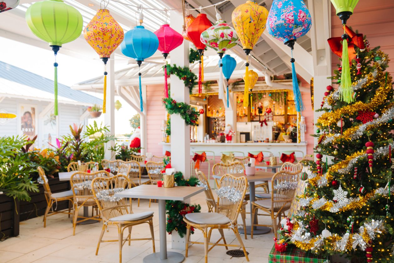 Colorful lanterns, decorated Christmas tree & festive furniture create a cheerful vibrant holiday-themed restaurant interior.