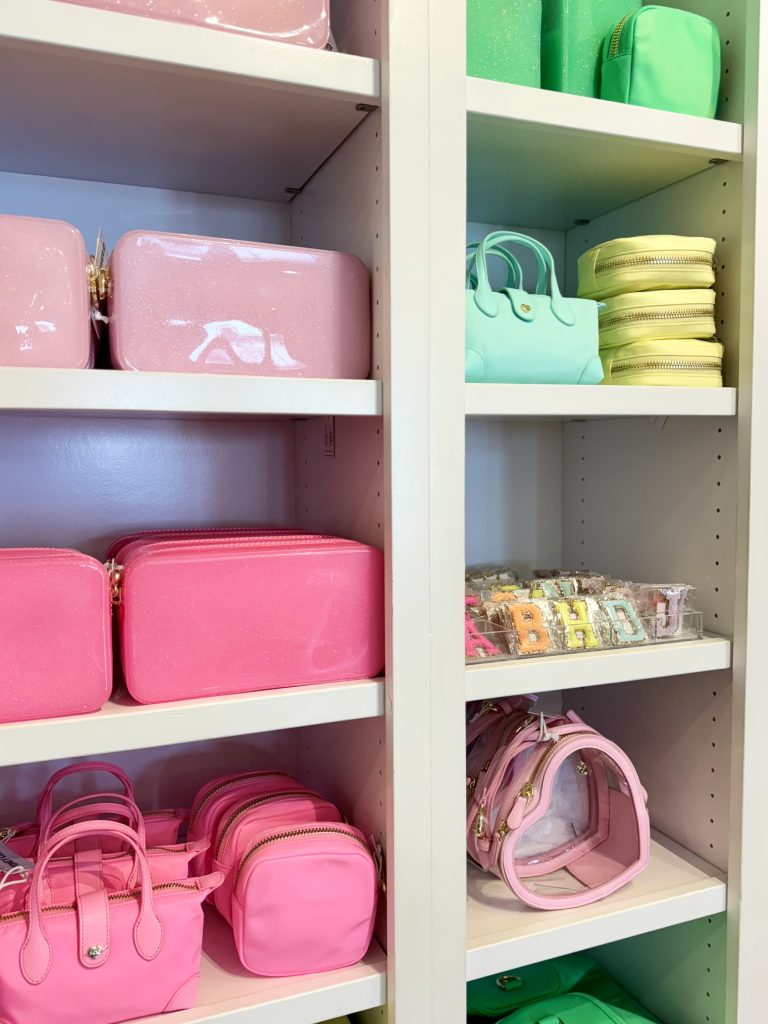 Shelves displaying colorful pastel handbags and pouches in pink, mint green, and yellow tones.