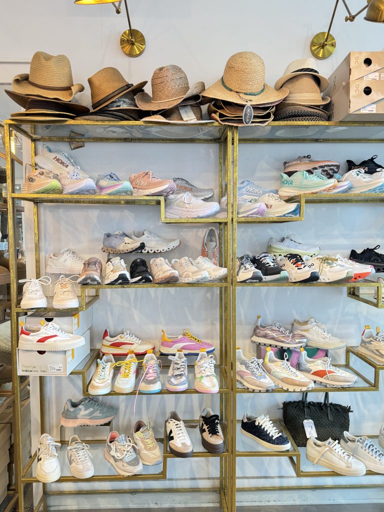 Display shelves with various stylish sneakers and straw hats, arranged neatly in a bright store setting.