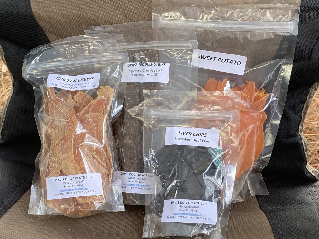 Assorted packaged dog treats including chicken chews, beef sticks, liver chips, and sweet potato slices.