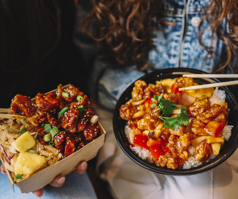 Two people holding saucy Asian street food bowls with chopsticks and rice.