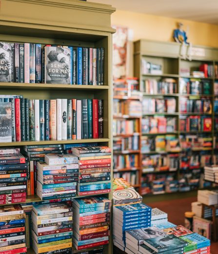 Bookshelves and stacked novels inside a cozy independent bookstore.