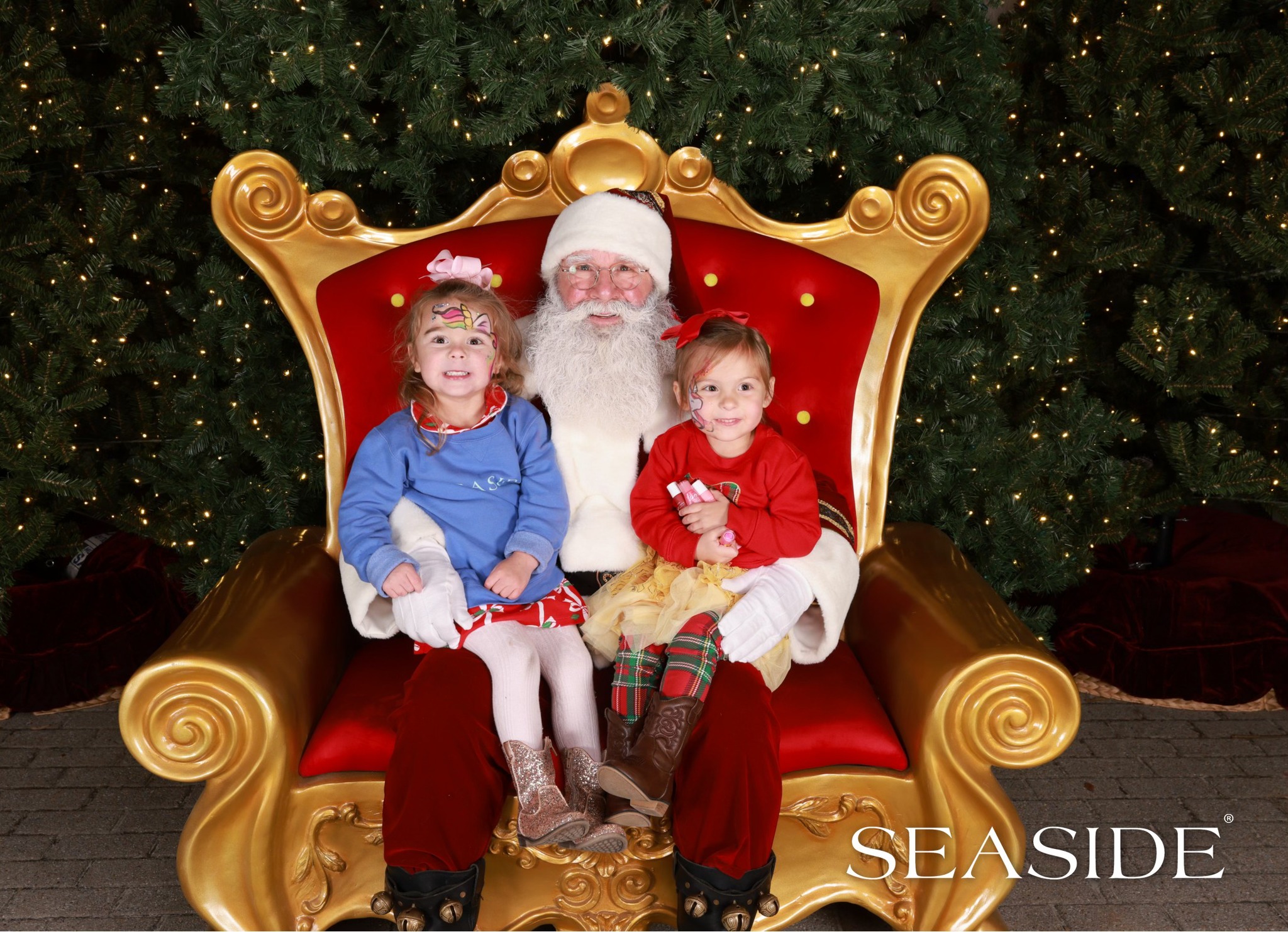Santa sitting on golden throne with two smiling, face-painted children at SEASIDE.
