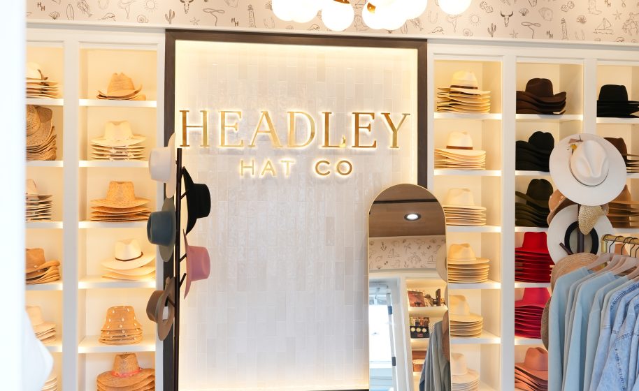 Stylish hat boutique interior with illuminated “Headley Hat Co” sign, neatly displayed hats, and mirror.