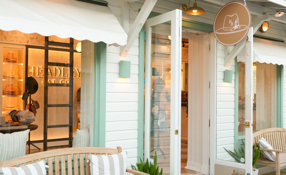 Charming boutique storefront with open doors, striped pillows on wooden benches, and warm lights illuminating the entrance.