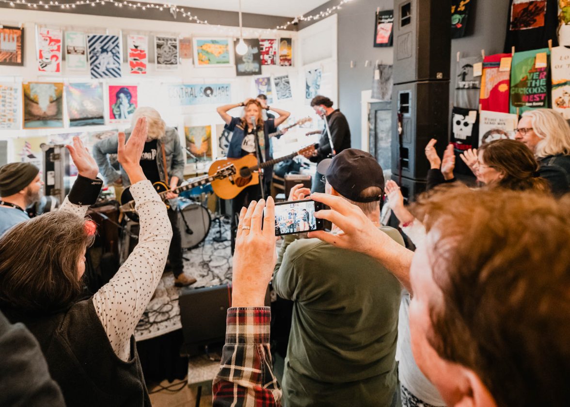 Crowd cheering and recording a live band performing in a small indoor venue.