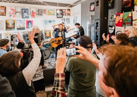Crowd cheering and recording a live band performing in a small indoor venue.