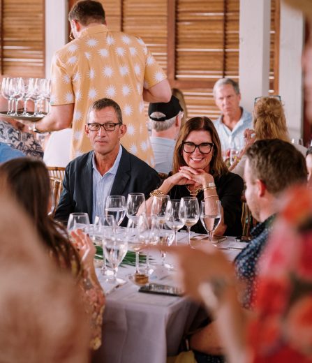 Guests seated at a dinner table enjoying conversation and wine indoors.