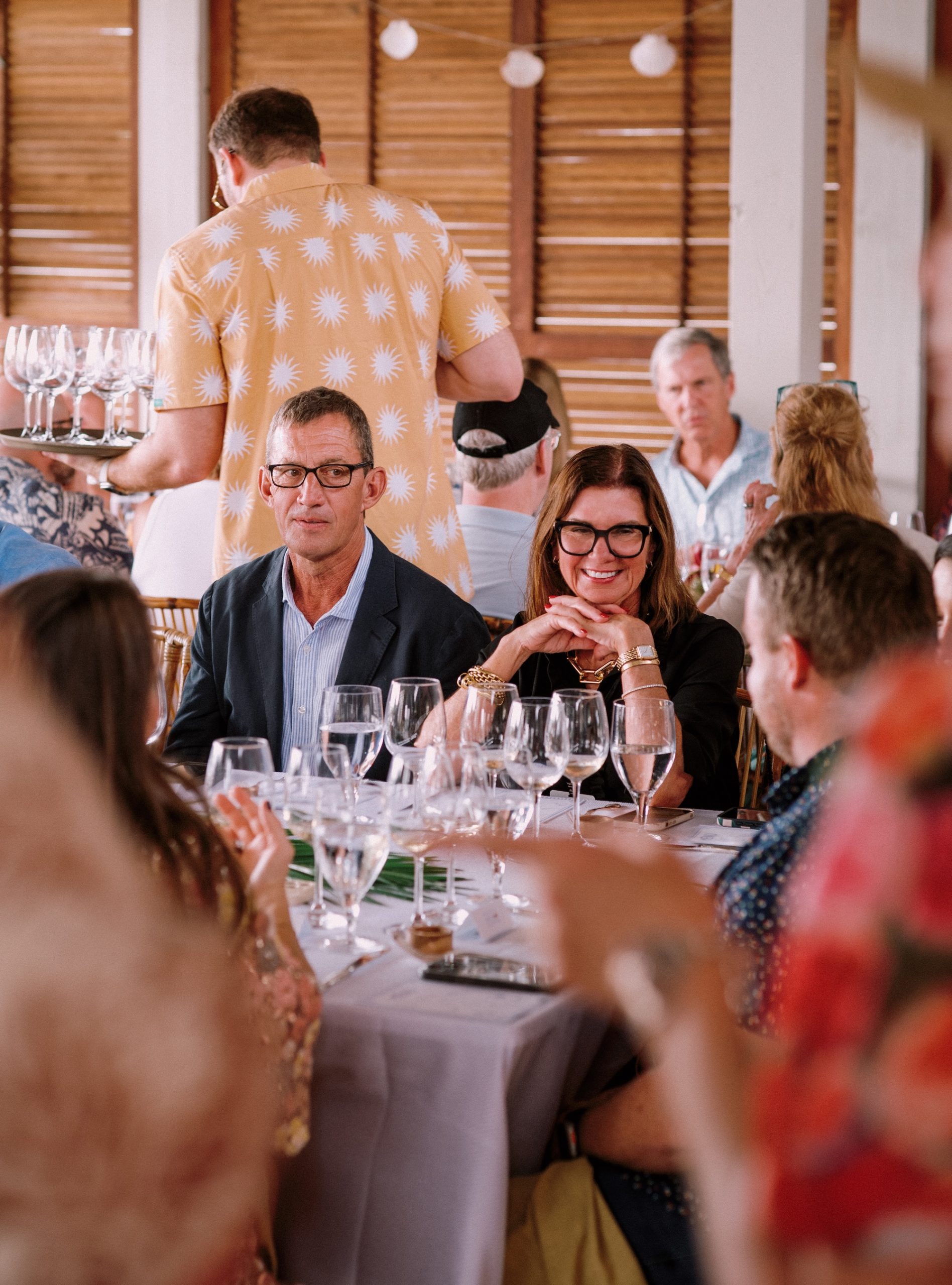 Guests seated at a dinner table enjoying conversation and wine indoors.