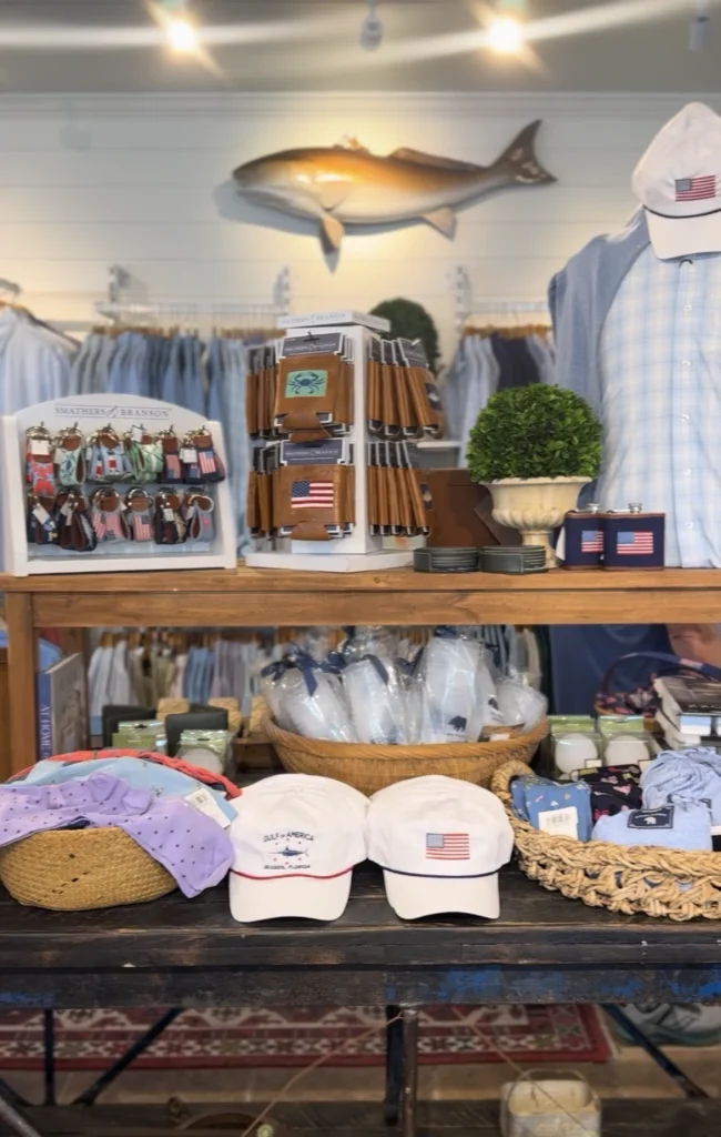 Retail display featuring patriotic hats, accessories, clothing, and a mounted fish on the wall.