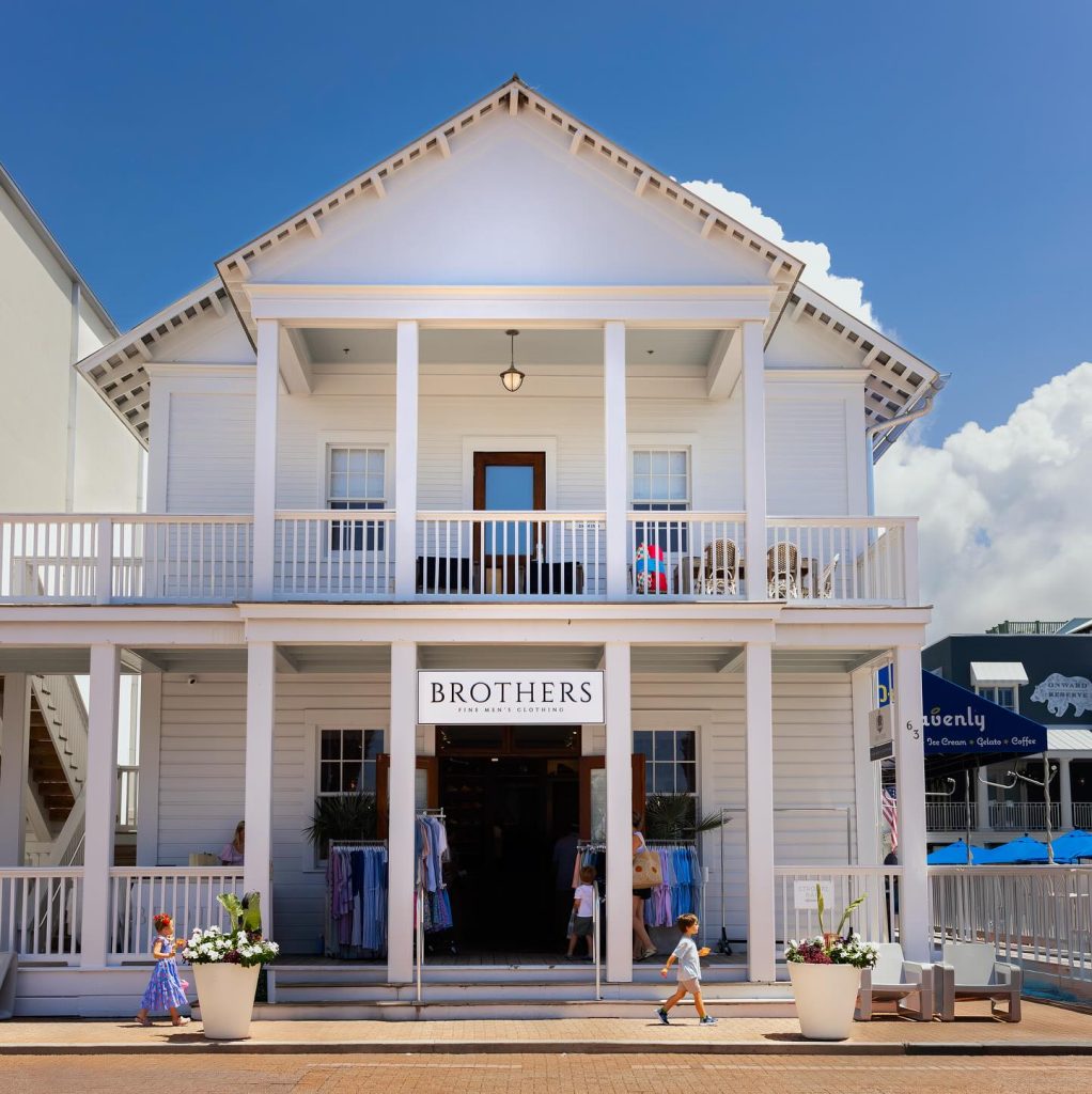 White two-story building with porch housing Brothers Fine Men’s Clothing store under a bright blue sky.