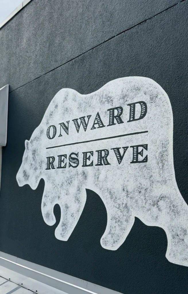 White bear silhouette mural on dark wall, with "Onward Reserve" in bold letters across the shape.