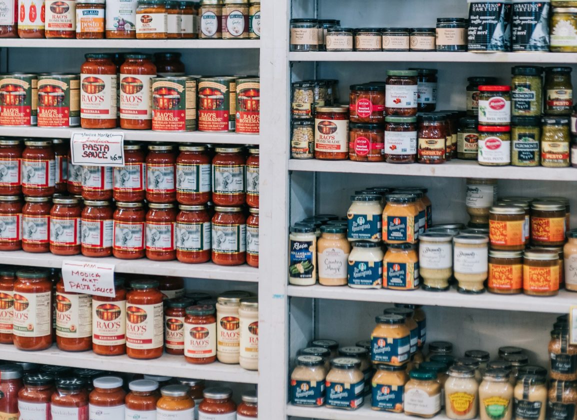 Shelves display jars of pasta sauces, condiments, and spreads in a grocery store or specialty market.