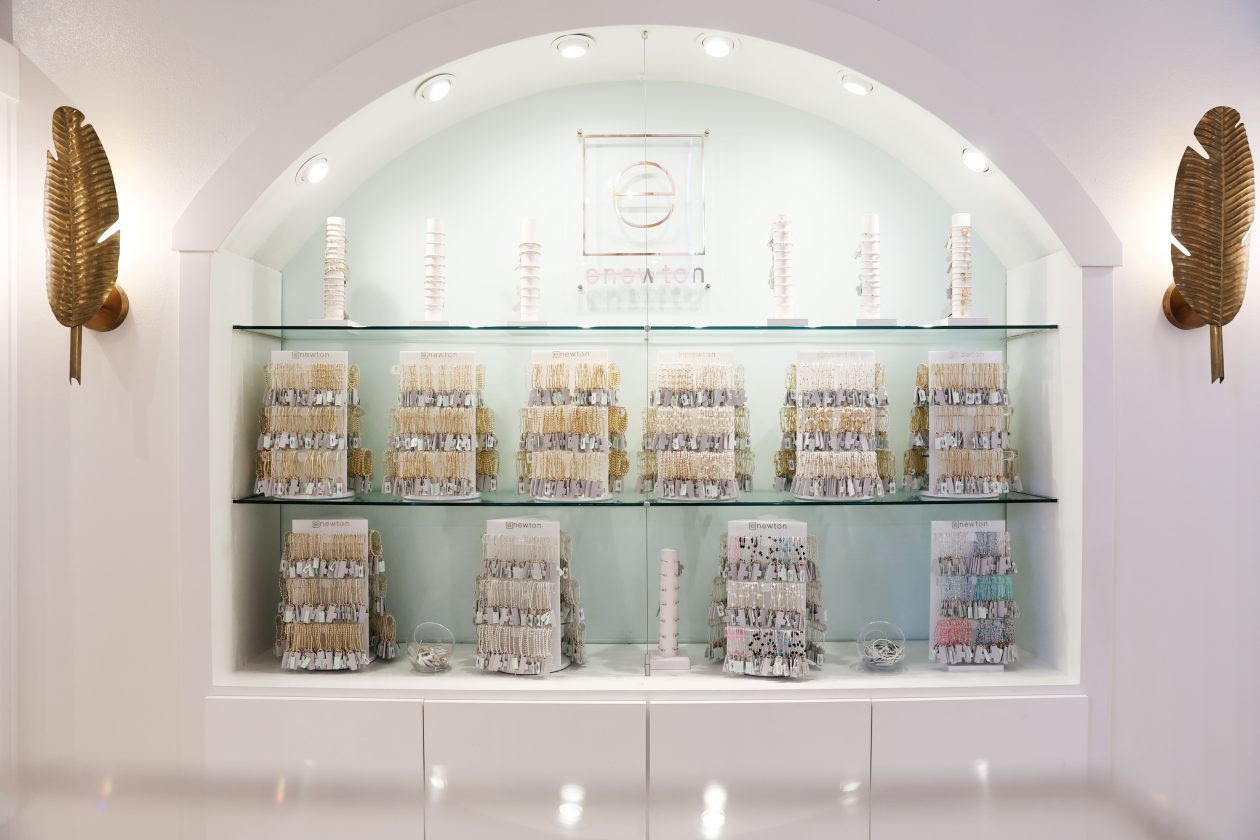Jewelry boutique display featuring organized bracelet collections on glass shelves beneath arched, softly lit alcove.