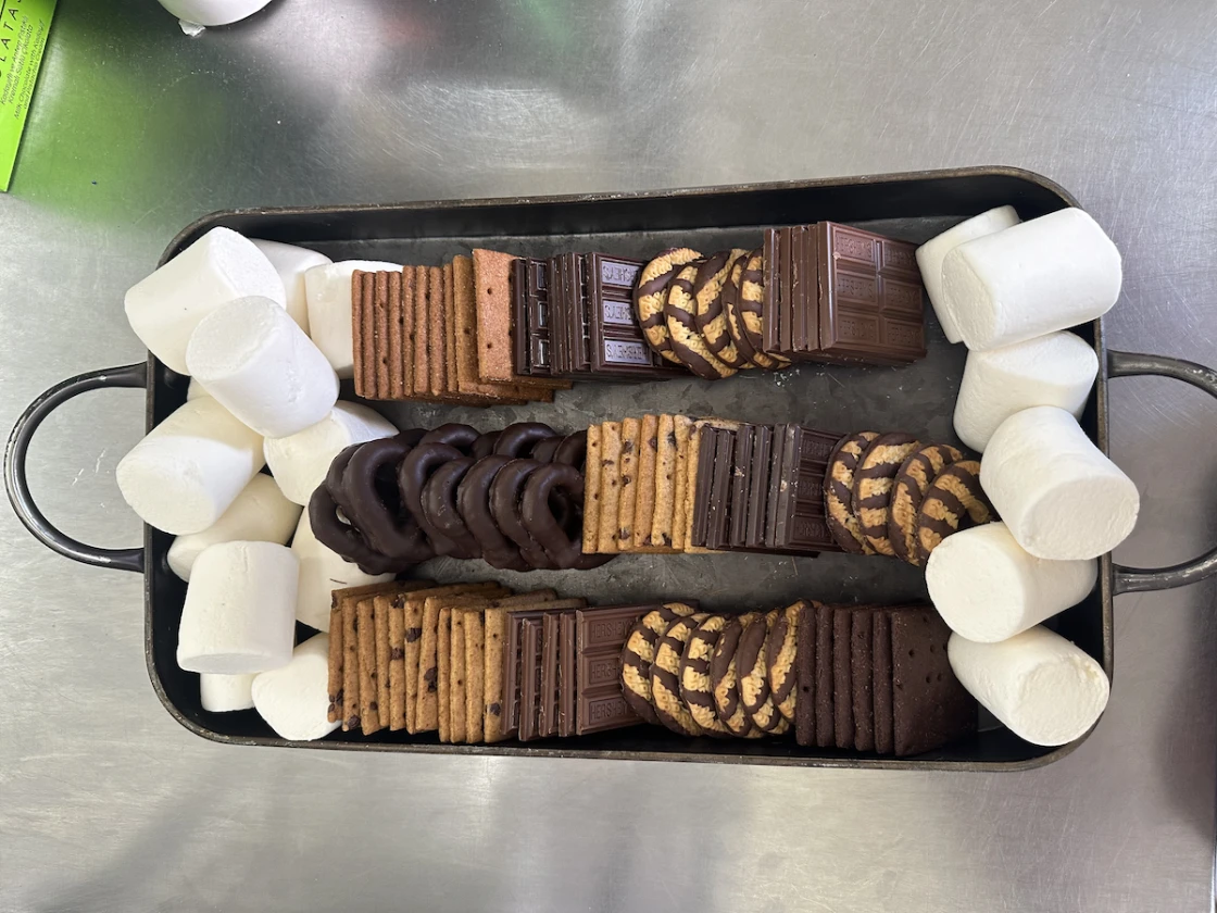 Tray of assorted chocolate cookies and graham crackers surrounded by large marshmallows.