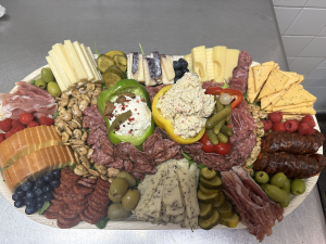 Large charcuterie platter with assorted cheeses, cured meats, olives, fruits, and spreads.