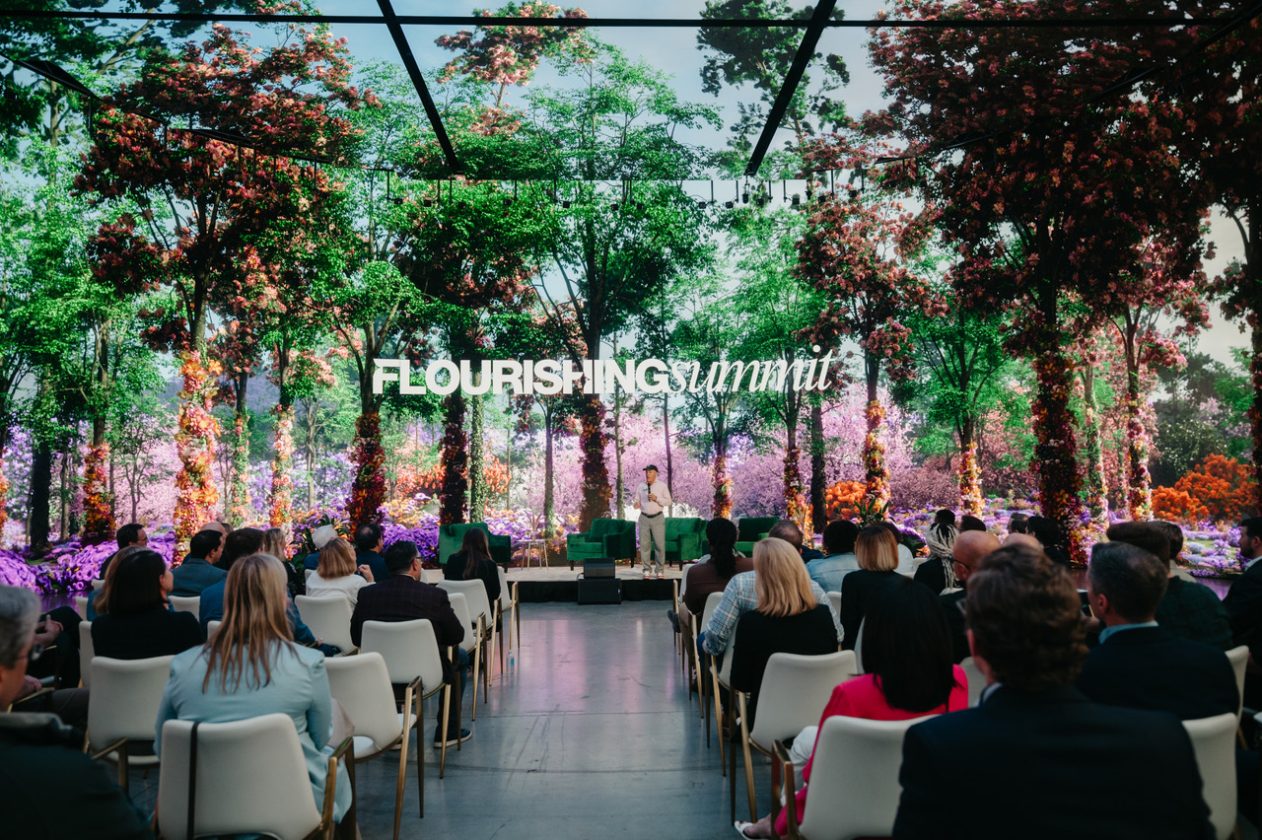 Audience attending Flourishing Summit keynote in immersive floral, nature-inspired event space.