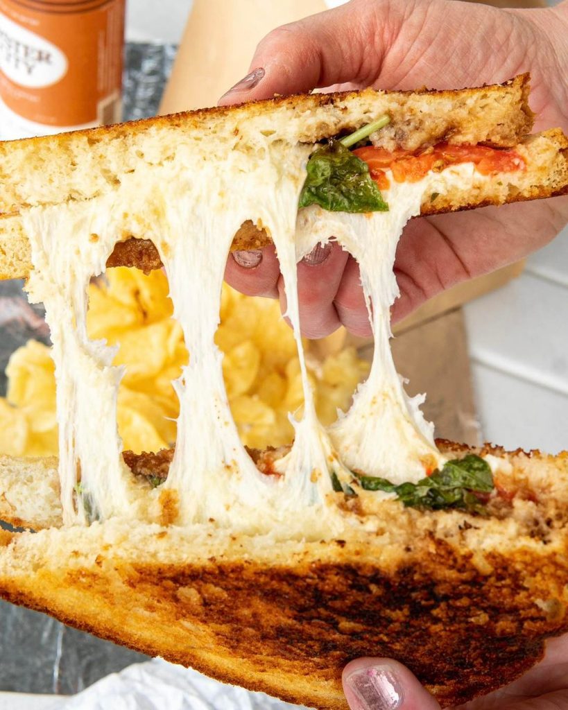 Close-up of a grilled cheese sandwich pulled apart, with melted mozzarella stretching between toasted bread slices.