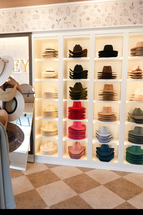 Hat boutique interior featuring neatly stacked colorful hats on illuminated shelves.