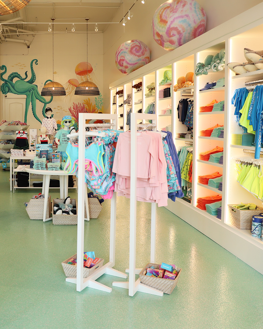 Bright beachwear boutique with colorful clothing displays, ocean-themed murals, and pastel decor.