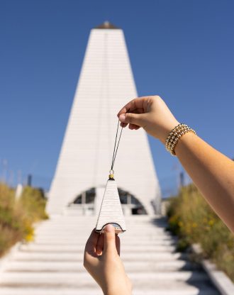 Hand holding a collectible Seaside Coleman Pavilion ornament in front of the actual pavilion