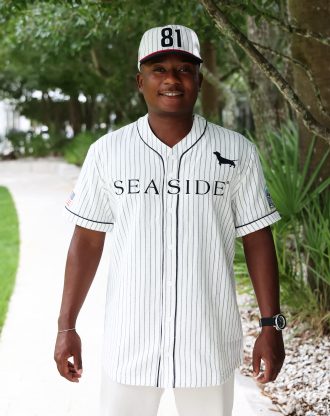 Man wearing a white pinstripe SEASIDE baseball jersey with dachshund logo and matching cap
